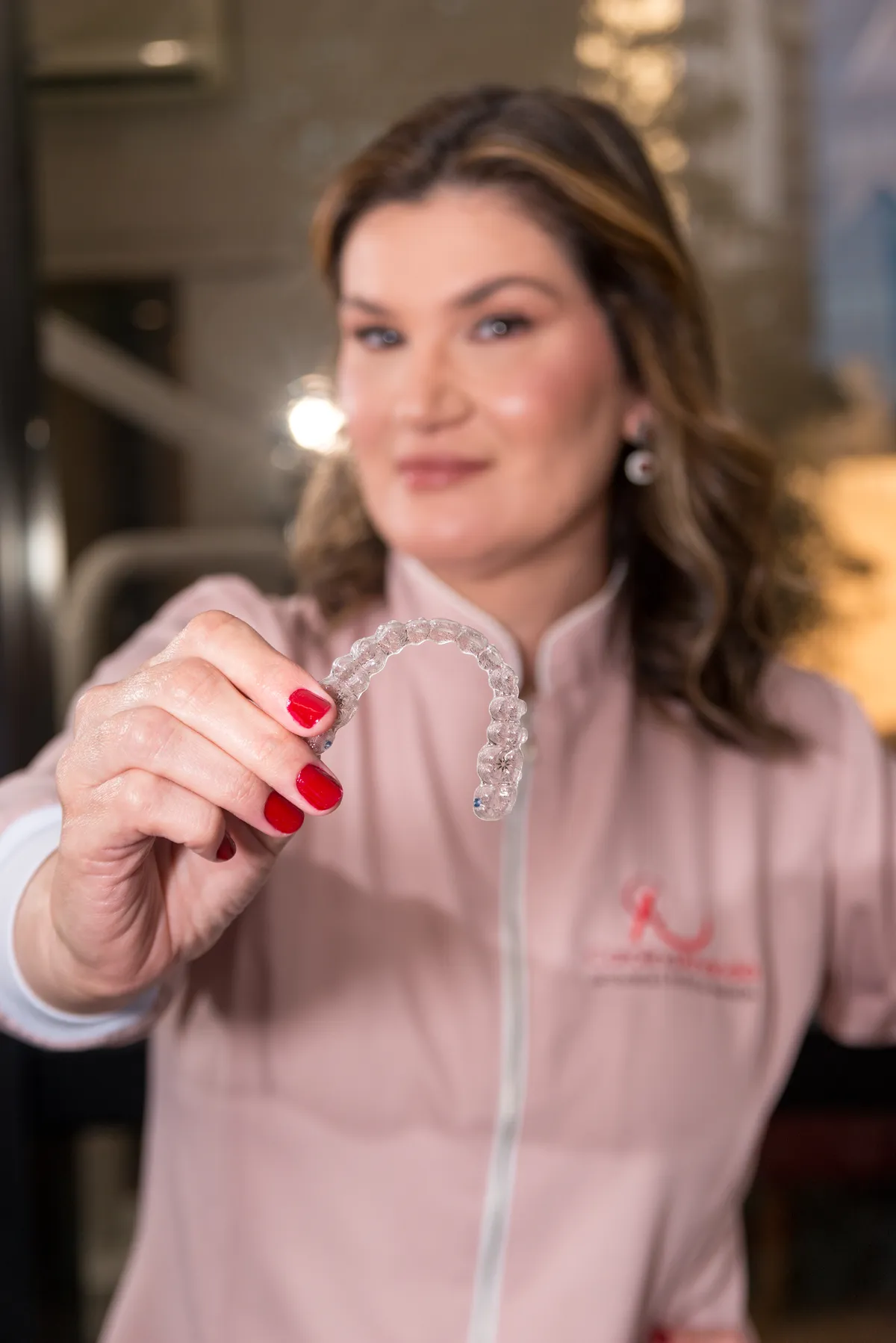 Dra. Carolina Ananda segura um alinhador transparente Invisalign